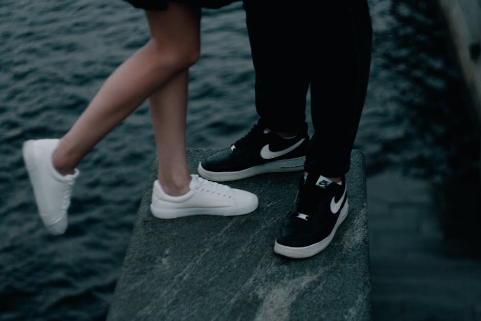 Close-up of white and black sneakers on a dock near a waterfront, conveying a casual vibe.